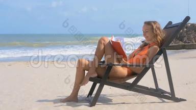 少女在Tranquil海洋海滩微笑主席席上阅读